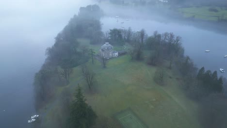 Approaching-drone-and-slowly-descending-down-on-a-secluded-residence-on-an-island-in-the-middle-of-the-Windermere-Lake,-in-United-Kingdom