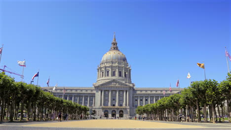 San-Francisco-City-Hall-on-a-clear-day,-flags-fluttering,-blue-sky