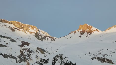 Atemberaubende-Drohnenperspektive,-Die-Die-Silhouette-Der-Schneebedeckten-Bergkette-Bei-Sonnenaufgang-Einfängt