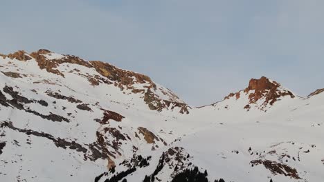 Sunrise-aerial-view-of-a-snowy-mountain-range-silhouette-captured-by-a-drone