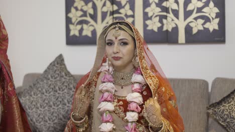Indian-Bride-In-Her-Bridal-Wear-Sitting-In-The-Couch-And-Smiles-To-Camera-Before-Her-Wedding