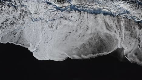 Top-down:-Foamy-Waves-of-Atlantic-Ocean-reaching-black-basalt-beach-of-Iceland-at-sunny-day