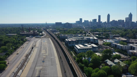 Drone-wide-shot-of-suburb-buildings-near-tracks-in-summer
