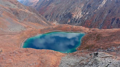 Lago-De-Montaña-Ubicado-En-Un-Valle-Otoñal,-Colores-Vibrantes-Que-Se-Reflejan-En-El-Agua,-Paisaje-Sereno