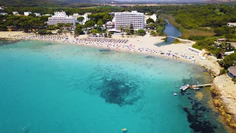 Crowded-canyamel-beach-with-turquoise-waters-on-a-sunny-day,-Mallorca,-Spain,-aerial-view