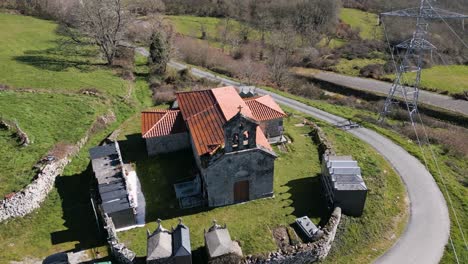Aerial-orbit-around-Church-of-Madanela-de-Cerdeira-in-San-Xoan-de-Rio,-Ourense,-Galicia,-Spain-with-graveyard