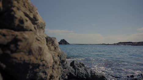 Dolly-shot-of-volcanic-rock-by-the-sea