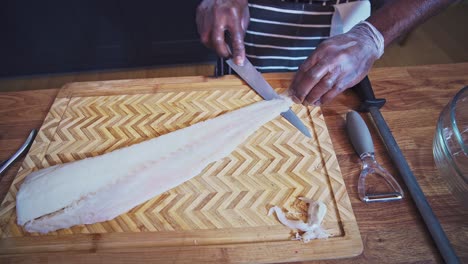 Chef-Caribeño-Preparando-Bacalao-En-Una-Tabla-De-Cortar