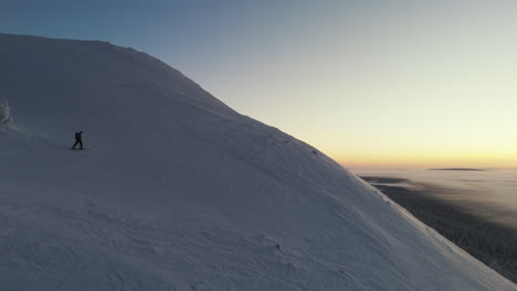 a-free-skier-climbing-to-the-top-while-the-colorful-sun-rises-from-behind-the-mountain