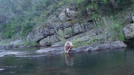 Un-Bosquimano-Limpia-Una-Trucha-Recién-Capturada-En-Un-Río-En-El-Monte-Australiano