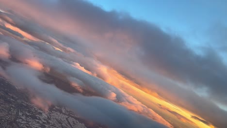 Pilot-FPV-POV-flying-through-a-cloudy-sky-full-of-orange-clouds-at-sunrise,-during-a-left-bank
