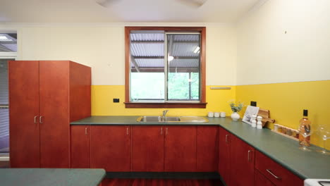 Rückwärts-Dolly-Im-Küchengang-Eines-Gelben,-Farbenfrohen-Hauses-Mit-Holzdielenschränken