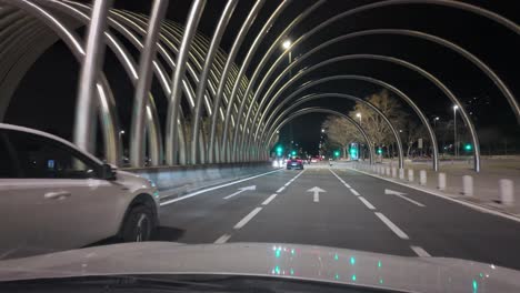 POV-Sicht,-Fahren-Bei-Nacht-Auf-Der-Großen-Allee-M-30,-Avenida-De-La-Ilustracion-In-Madrid,-Vorbei-Unter-Einem-Großen-Tor-Mit-Bogenstruktur-Und-Skulpturillustration