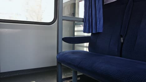 Inside-of-moving-train,-empty-blue-passenger-seat-in-compartment-close-up
