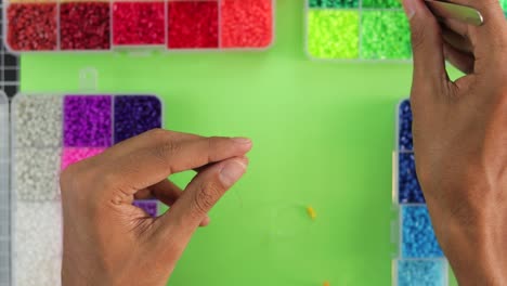 Nahaufnahme-Von-Händen,-Die-Eine-Regenbogenkette-Mit-Bunten-Perlen-Herstellen,-Lebendiges-Kreatives-Hobby