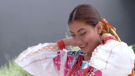 Filmclip-Einer-Jungen-Brünette-Latina-In-Der-Traditionellen-Tracht-Namens-Cayambeñas,-Die-Ihre-Rote-Halskette-Anzieht-Und-Lächelt