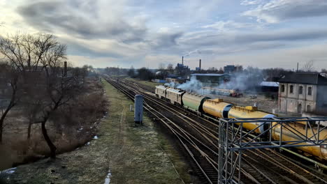 Eine-Rauchende-Diesellokomotive-Bewegt-Sich-Langsam-Davon,-Während-Sie-Eine-Lange-Reihe-Von-Kesselwagen-Zieht