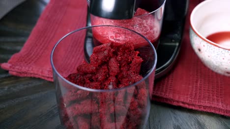 Close-up-of-beets-being-juiced-and-beet-pulp-falling-out-inside-of-a-container-making-dessert-beet-muffin