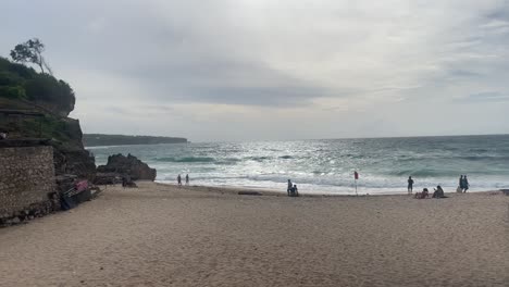 Camera-pasting-around-on-a-windy-beach-in-Bali-in-the-rainy-season-as-people-walking-around