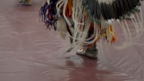 Intrincado-Juego-De-Pies-De-Bailarines-Adornados-Con-Elaborados-Trajes-Tradicionales-En-El-Powwow-De-La-Universidad-De-Las-Naciones-Indias-De-Haskell-En-Lawrence,-Kansas