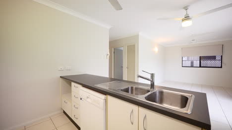 Empty-Kitchen-and-Vacant-Lounge-Area-with-small-thin-sink-and-dishwasher-in-apartment-building