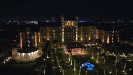 Drone-flying-in-front-of-the-illuminated-Grand-Galvez-resort,-in-Galveston,-USA