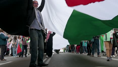 Demonstranten-Gehen-Während-Eines-Solidaritätsmarsches-Mit-Palästina-Unter-Einer-Großen-Palästinensischen-Flagge-Hindurch