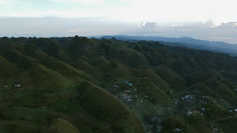 Osmena-peak-at-dusk-with-verdant-hills-and-scattered-rural-community,-aerial-view