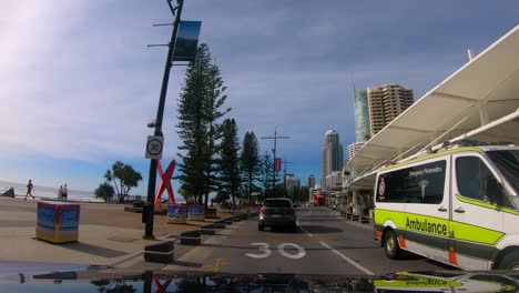 Point-of-view-driving-through-Surfers-Paradise-along-the-Esplanade-past-Cavill-Ave-next-to-the-beach,-Gold-Coast