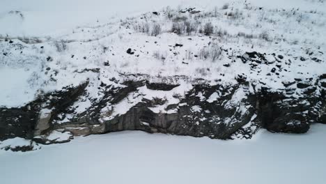 Slow-Moving-4K-Drone-Shot-of-Snow-covered-rock-inside-an-a-gravel-quarry-in-cold-weather-area