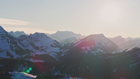 Snowy-mountain-range-silhouette-revealed-in-the-dawn-light-from-a-drone's-perspective