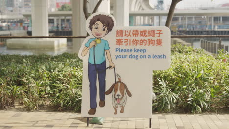 Handheld-shot-of-cartoon-sign-in-dog-park-with-Chinese-and-English-on-sidewalk