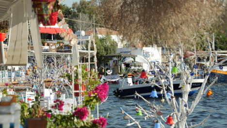 Barco-Flotando-En-El-Mar-Detrás-De-Las-Plantas-En-El-Restaurante-Frente-Al-Mar-En-Gumusluk,-Turquía.