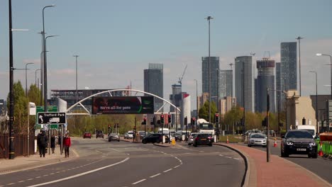 City-traffic-in-Manchester-with-pedestrians-and-modern-skyline-in-background,-clear-day