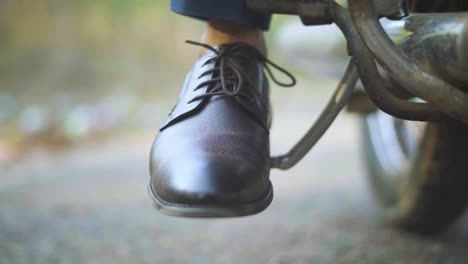 Closeup-shot-of-a-man-trying-to-kick-start-an-old-motorbike