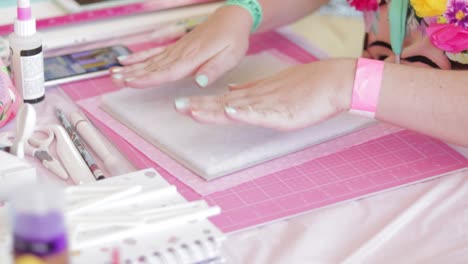 Hände-Erstellen-Ein-Scrapbook-Auf-Rosa-Matte-Mit-Bastelwerkzeugen-Herum,-Leuchtende-Farben