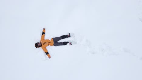 Un-Hombre-Con-Una-Chaqueta-Amarilla-Para-La-Nieve-Vuelve-A-Caer-En-La-Nieve-Para-Hacer-Un-ángel.