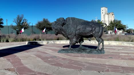 Buffalo-statue-and-Texas-state-flags-in-the-background-at-Frontier-Texas-in-Abilene,-Texas-and-stable-video-wide-shot
