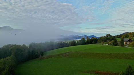 Nube-De-Niebla-Sobre-Una-Colina-Verde-Con-Cabaña-En-El-Campo-Alpino