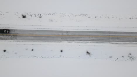 A-Top-Down-Black-Offroad-Pickup-Truck-Car-Driving-Under-Static-Drone-Shot-on-a-Winter-Snow-Covered-Highway-Road
