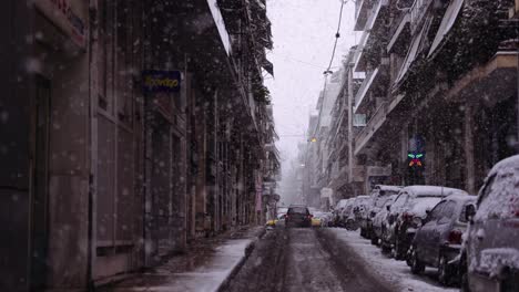 slow-motion-cinematic-urban-shot-of-a-car-in-a-road-while-snowing-in-downtown-Athens-cit-,-snowflakes-everywhere