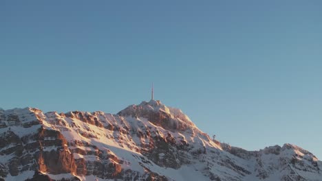Mesmerizing-drone-footage-displaying-the-silhouette-of-a-snowy-mountain-range-during-sunrise