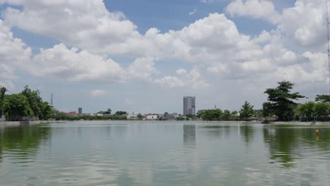Lake-With-City-Buildings-And-Clouds-In-The-Sky-In-The-Background