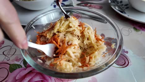 Elderly-broad-housewife-mixing-salad-with-vegetables-and-fruits-with-forks