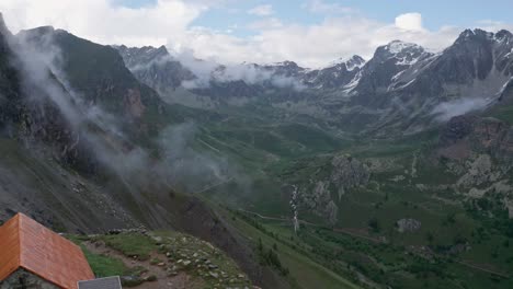 Refugio-De-Montaña-Solitario-En-Medio-De-Picos-Alpinos-Brumosos,-Un-Escape-Sereno-En-La-Naturaleza,-Luz-Del-Día,-Plano-Amplio