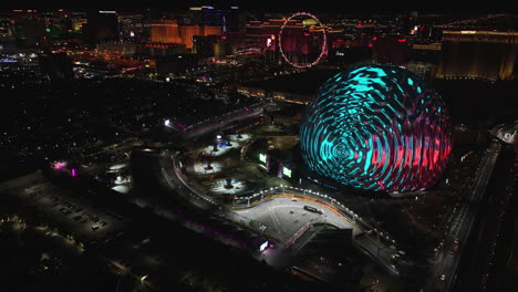 Drone-diving-over-the-flashing-Formula-1-track-at-the-Sphere,-night-in-Las-Vegas