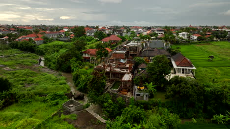 Villas-in-Bali-countryside-surrounded-by-lush-rice-fields,-aerial-arc