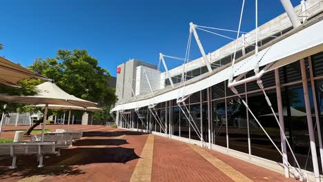 Caminando-Junto-Al-Exterior-De-Vidrio-Curvo-Del-Edificio-Del-Campus-Universitario-De-Diseño-De-Arquitectura-Moderna