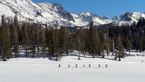 Cross-Country-Skiers-on-Snowy-Trail-with-Mountain-Backdrop