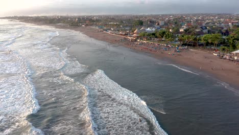 Drone-shot-of-famous-surf-beach-Canggu-with-sunset-golden-light-and-waves-in-Bali,-Indonesia